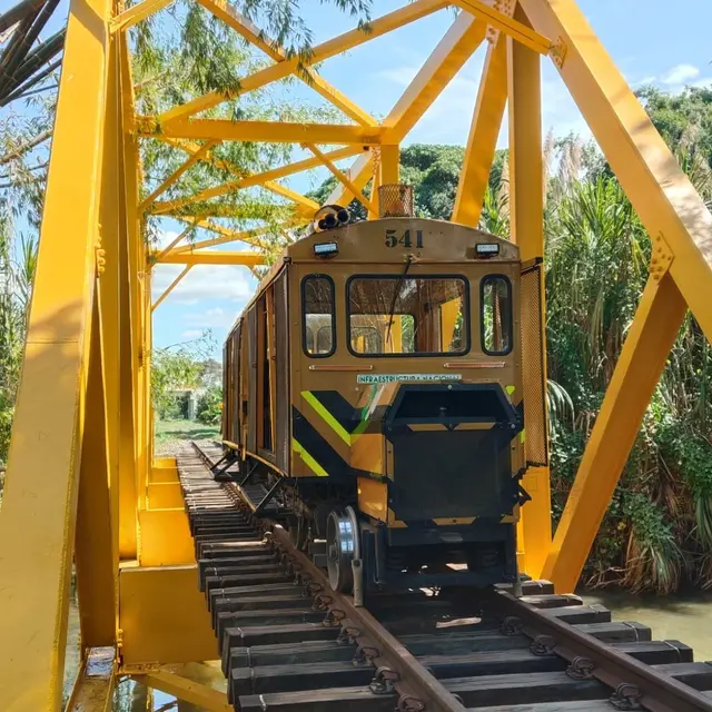Vehículo ferroviario sobre un puente metálico amarillo