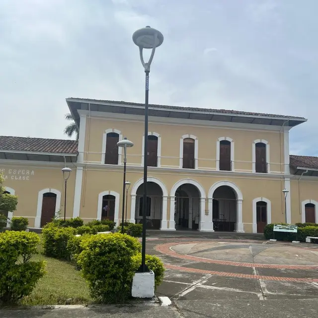 Edificio de una estación del ferrocarril con jardines al frente