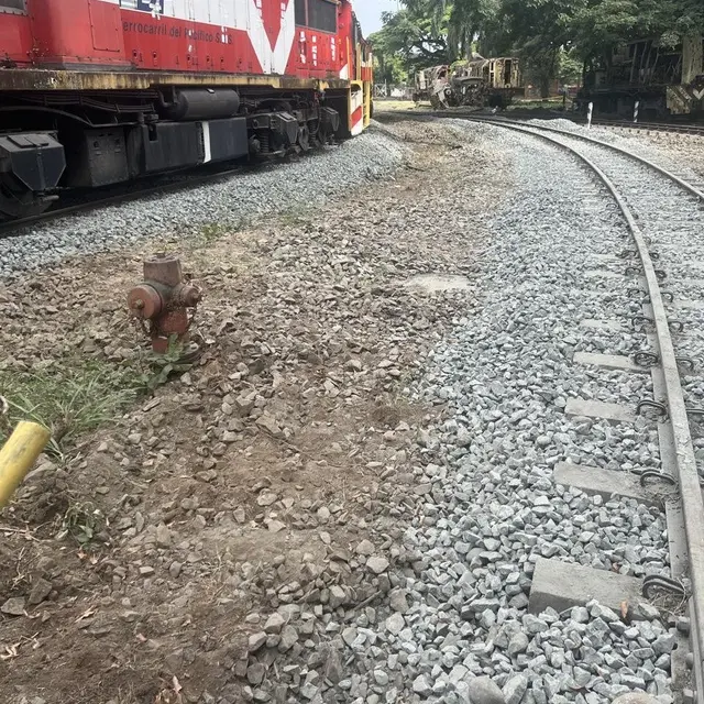 Vía con balasto nuevo junto a una locomotora roja